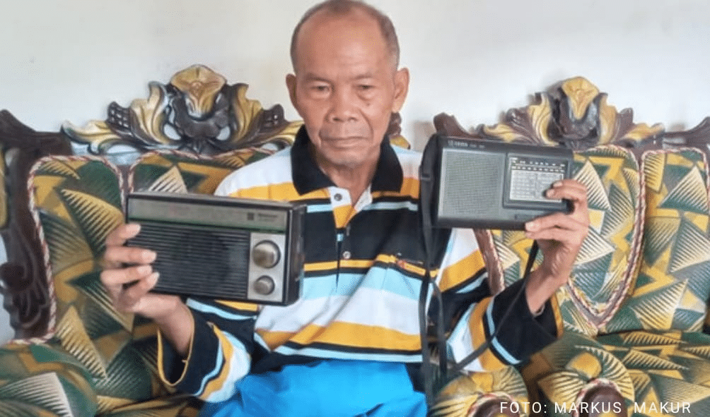 Pensiunan Guru, Damianus Anam (77) sedang mendengarkan siaran radio sambil memegang dua radio bekas yang tak bisa dipakainya karena rusak. (DOK/Markus Makur)